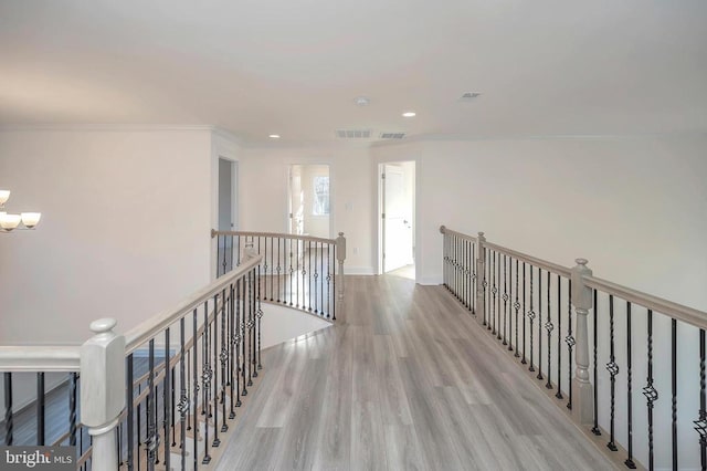  - corridor with an upstairs landing, wood finished floors, a chandelier, crown molding, and recessed lighting