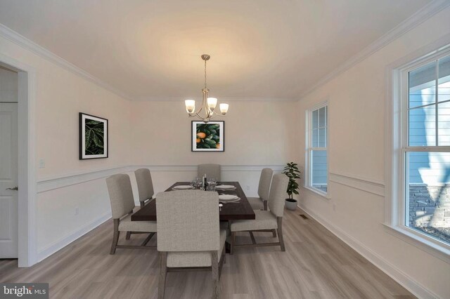 - dining space featuring light wood-type flooring, a chandelier, plenty of natural light, and ornamental molding