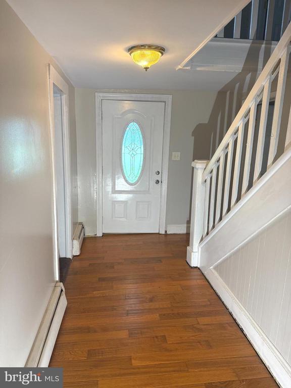  - entryway featuring a baseboard heating unit, wood finished floors, and stairway