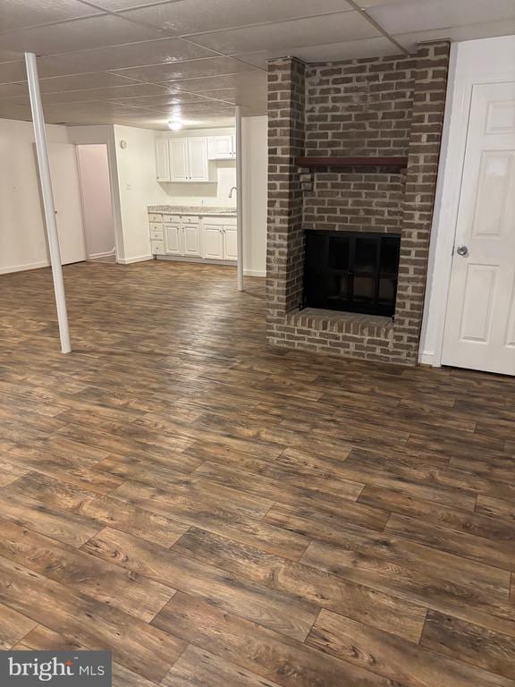  - unfurnished living room featuring dark wood finished floors, baseboards, and a brick fireplace