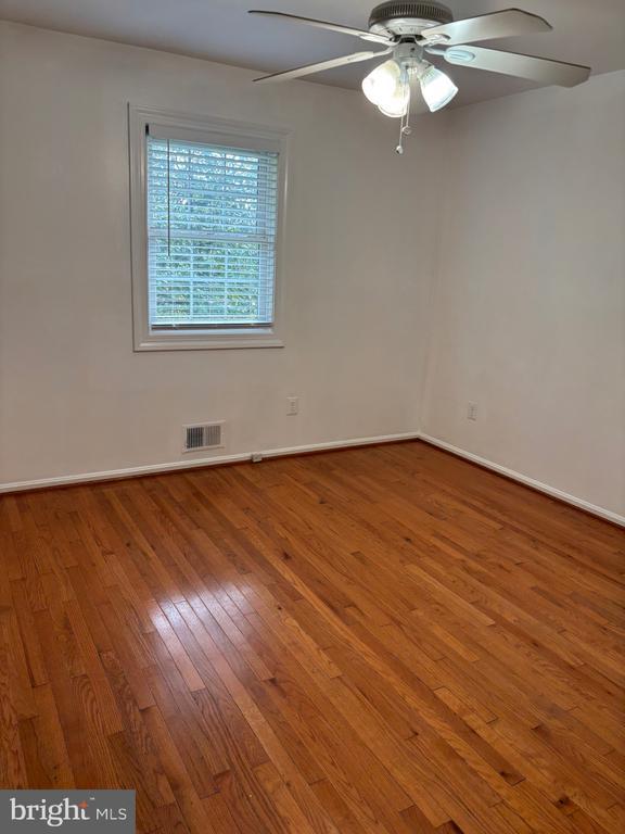  - spare room with hardwood / wood-style flooring, a ceiling fan, and baseboards