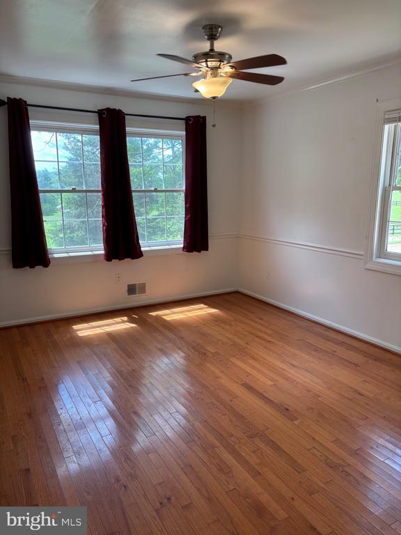  - unfurnished room with hardwood / wood-style floors, ceiling fan, and baseboards