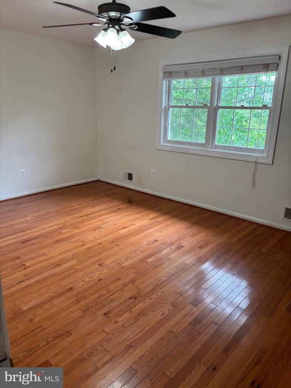  - unfurnished room featuring hardwood / wood-style flooring, ceiling fan, and baseboards