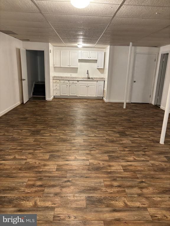  - unfurnished living room featuring a sink, dark wood-type flooring, and baseboards