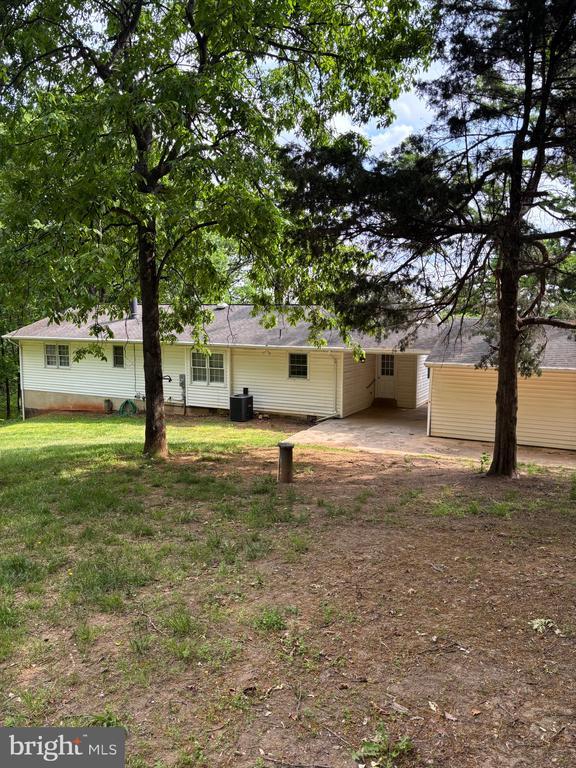  - rear view of property featuring an attached carport and a lawn
