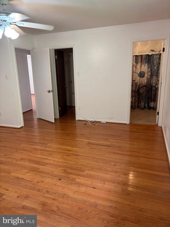  - unfurnished bedroom featuring light wood-style floors, baseboards, and a walk in closet
