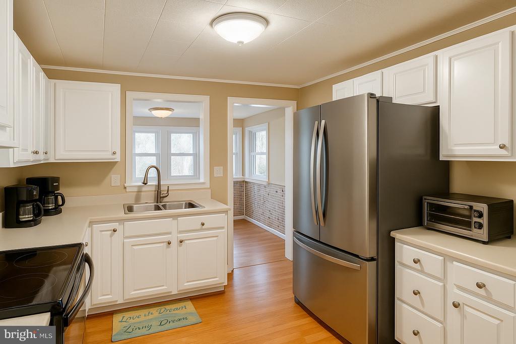 335 Deer Crossing Ln, Orange, VA 22960 - kitchen with a sink, light wood finished floors, freestanding refrigerator, white cabinetry, and light countertops