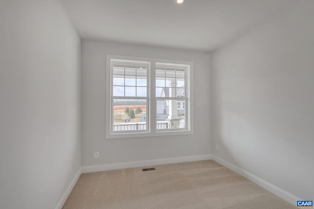 empty room with light colored carpet, visible vents, and baseboards