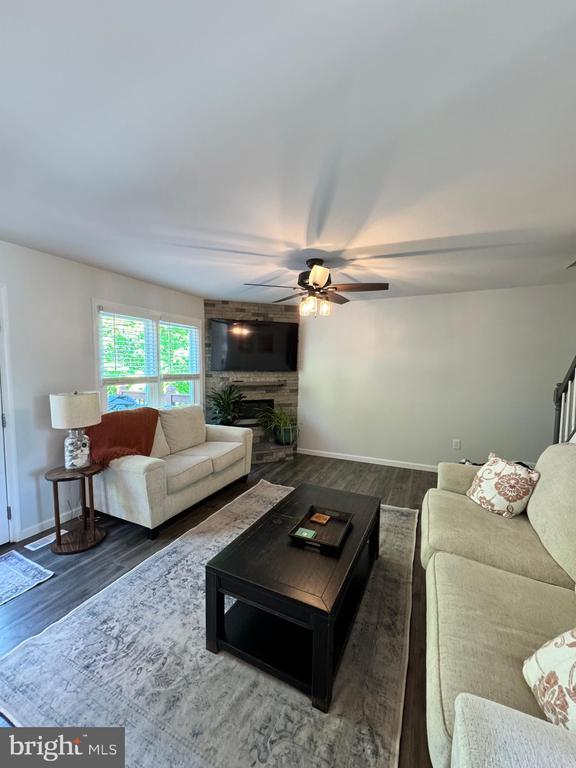 10010 Peppermill Ct, Fredericksburg, VA 22407 - living room with wood finished floors, ceiling fan, a large fireplace, and baseboards