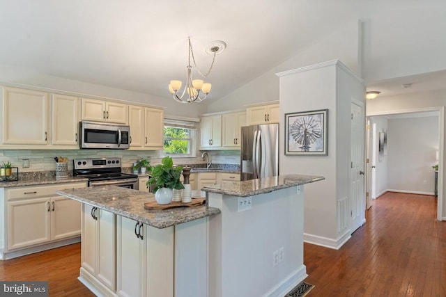  - kitchen with appliances with stainless steel finishes, a chandelier, tasteful backsplash, a kitchen island, and lofted ceiling