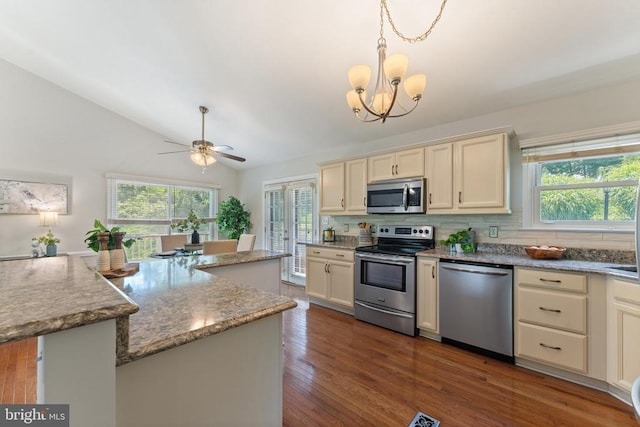  - kitchen featuring appliances with stainless steel finishes, backsplash, dark wood-style floors, a chandelier, and light stone countertops