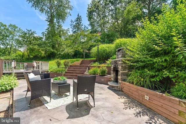  - view of patio with stairs, an outdoor stone fireplace, outdoor dining area, view of wooded area, and a wooden deck