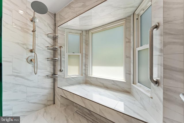  - bathroom featuring a tile shower and marble finish floors
