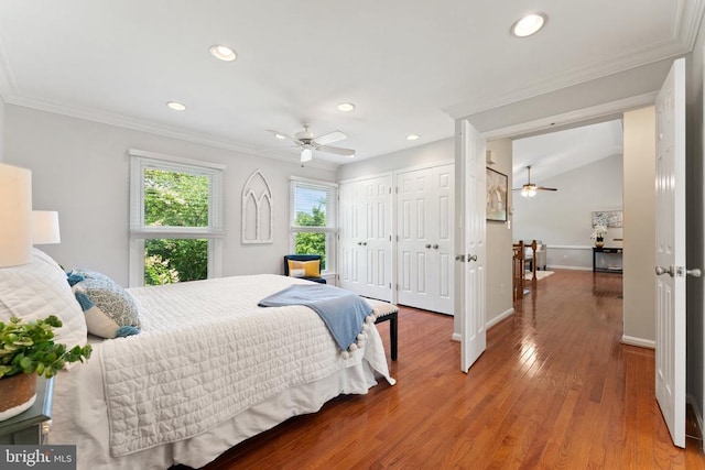  - bedroom featuring multiple closets, ornamental molding, recessed lighting, and wood finished floors