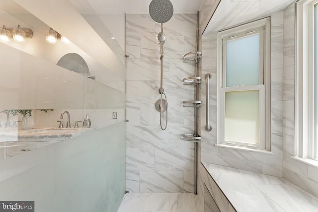  - bathroom featuring a tile shower and a sink