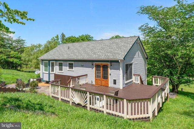  - rear view of house featuring roof with shingles, a deck, and a lawn