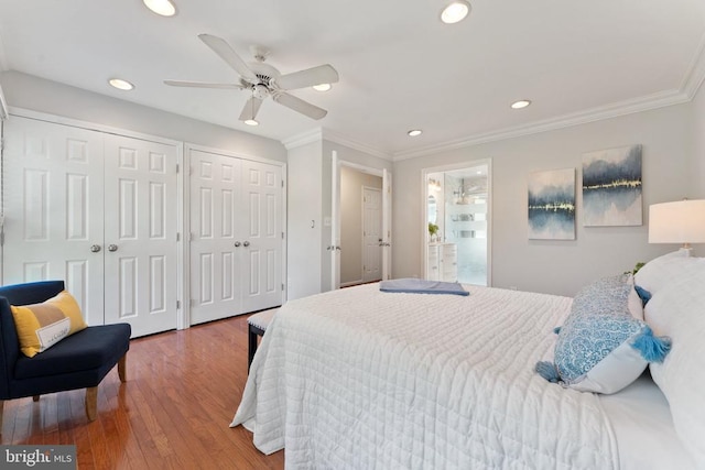  - bedroom featuring two closets, wood finished floors, recessed lighting, ornamental molding, and ceiling fan