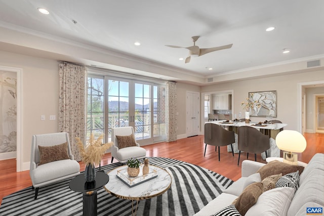 living area featuring crown molding, baseboards, and light wood-type flooring