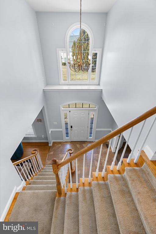 foyer with a chandelier, stairway, wood finished floors, baseboards, and a towering ceiling