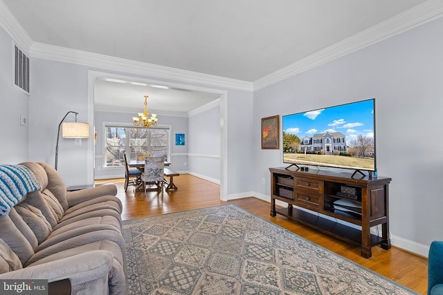living area featuring a chandelier, wood finished floors, crown molding, and baseboards