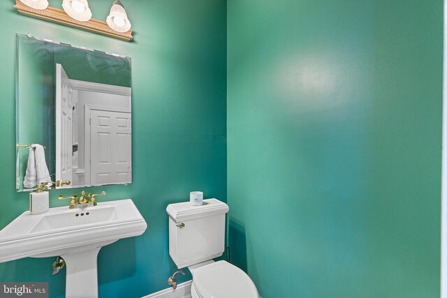 bathroom with toilet, baseboards, and a sink