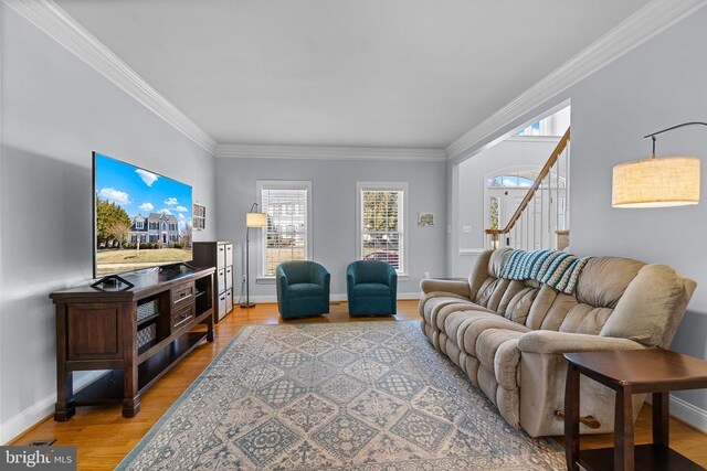 living area featuring ornamental molding, light wood finished floors, healthy amount of natural light, stairs, and baseboards