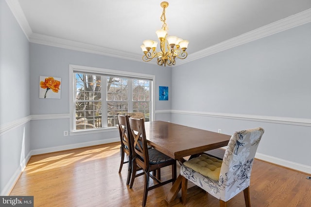 dining space featuring a chandelier, wood finished floors, baseboards, and crown molding