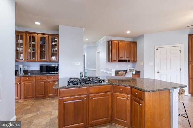 kitchen featuring stainless steel microwave, a center island, gas cooktop, glass insert cabinets, and recessed lighting