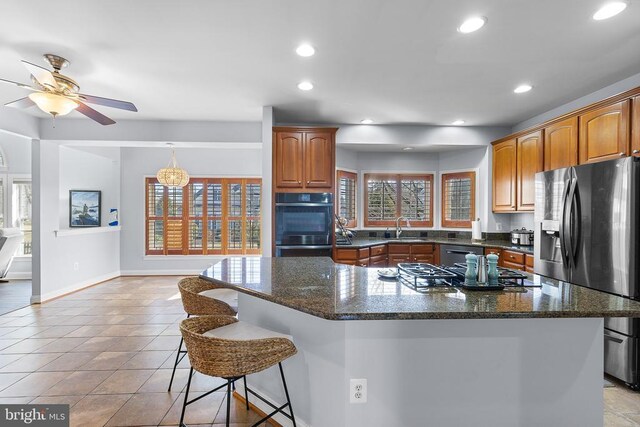 kitchen featuring stainless steel appliances, a ceiling fan, baseboards, a kitchen bar, and a center island