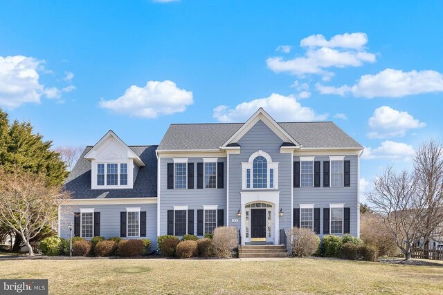 colonial-style house with a front lawn and roof with shingles