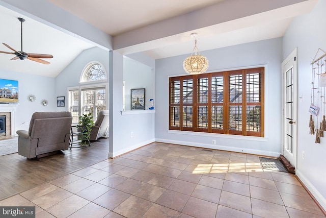 tiled foyer featuring ceiling fan, baseboards, lofted ceiling, and a glass covered fireplace