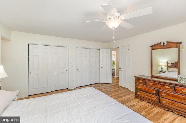 bedroom featuring two closets, light wood-type flooring, ceiling fan, and baseboards