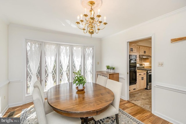 dining room with a chandelier, light wood-style flooring, and ornamental molding