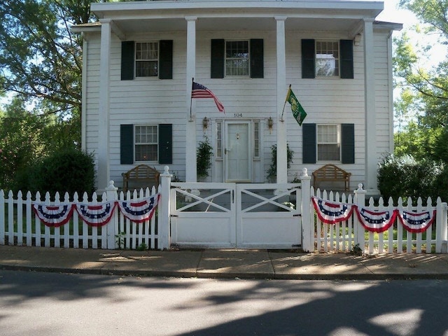 neoclassical home with a fenced front yard, a porch, and a gate
