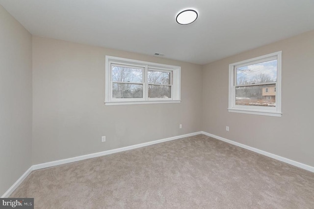 spare room featuring light colored carpet and a healthy amount of sunlight