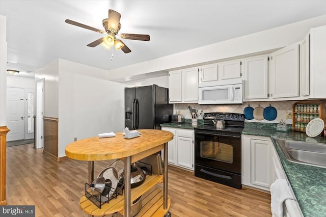 319 Fox Hunters Ln, Madison, VA 22727 - kitchen featuring black range with electric stovetop, white microwave, light wood-style floors, and dark countertops