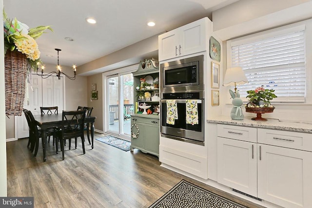 kitchen featuring an inviting chandelier, appliances with stainless steel finishes, wood finished floors, and white cabinetry