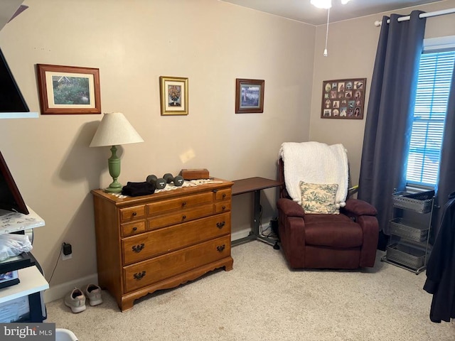 living area featuring light colored carpet, baseboards, and ceiling fan