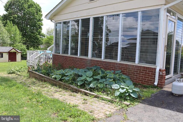 view of side of home featuring brick siding, an outdoor structure, and a storage shed