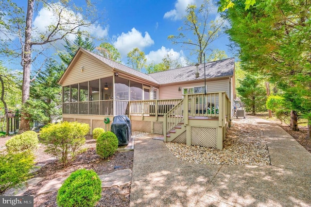 back of property with a sunroom, central AC, a wooden deck, stairs, and roof with shingles