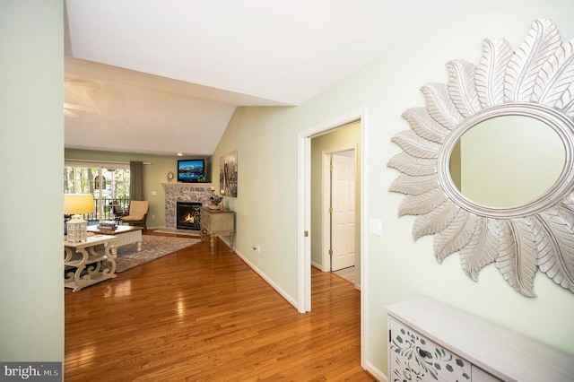 corridor with lofted ceiling, light wood-type flooring, and baseboards