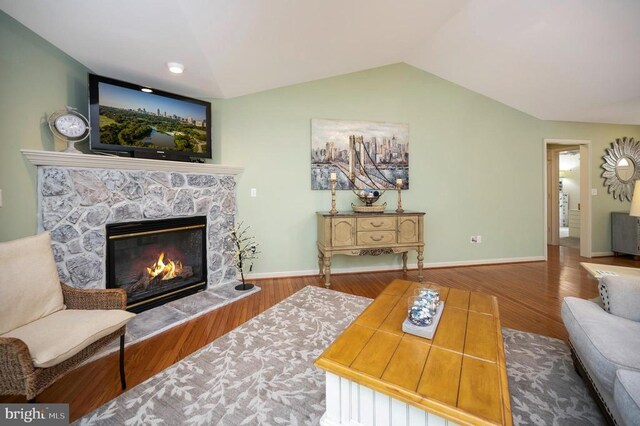 living room with wood finished floors, a premium fireplace, lofted ceiling, and baseboards