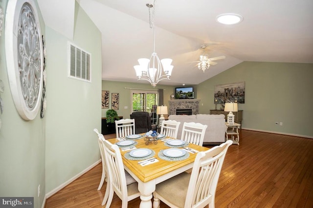 dining room featuring lofted ceiling, ceiling fan, wood finished floors, a fireplace, and baseboards