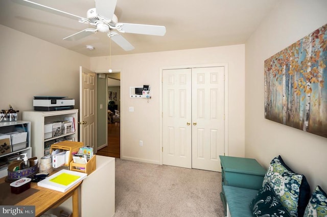 office area featuring a ceiling fan, light colored carpet, and baseboards