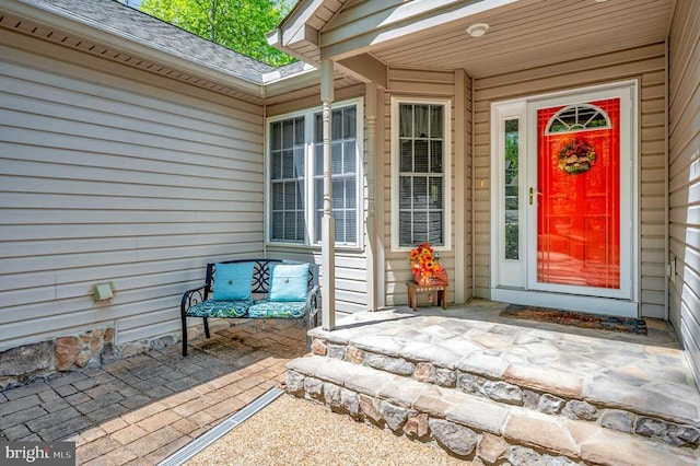 entrance to property featuring roof with shingles