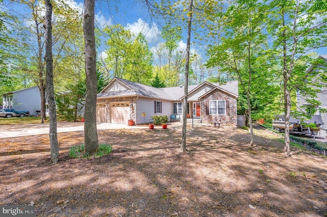 ranch-style home with an attached garage, concrete driveway, and stone siding