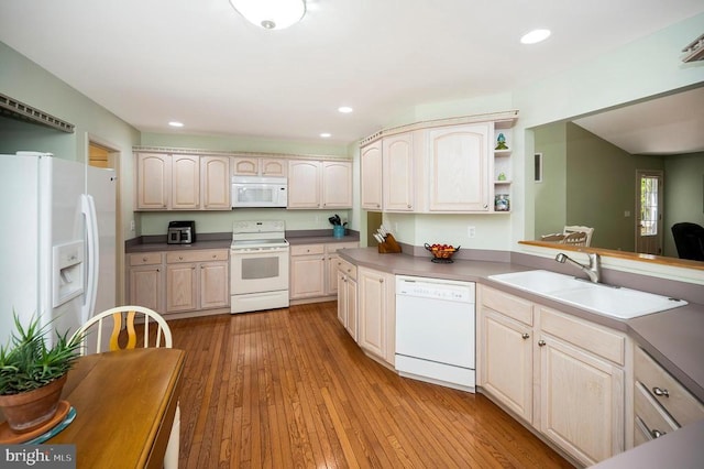 kitchen with white appliances, a sink, recessed lighting, light wood-style flooring, and dark countertops