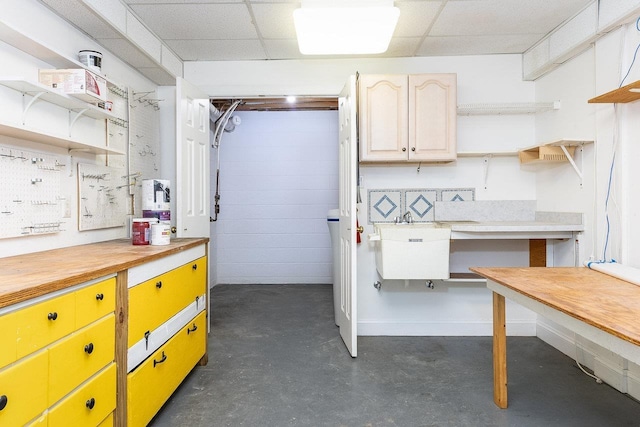 basement with a workshop area, a paneled ceiling, and a sink