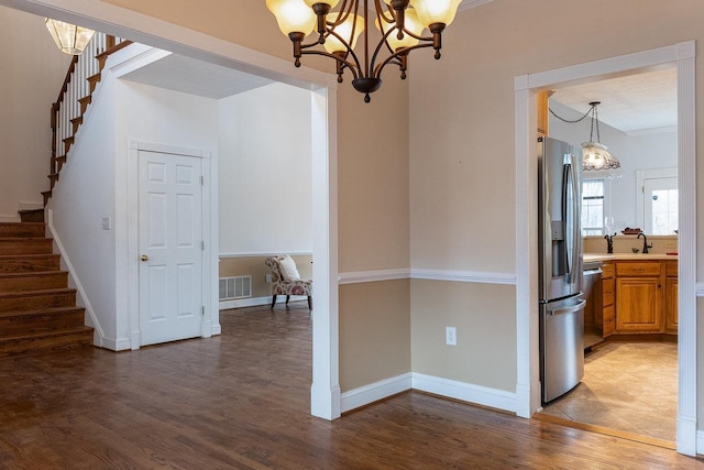 unfurnished dining area with light wood-style flooring, a sink, a notable chandelier, visible vents, and stairway