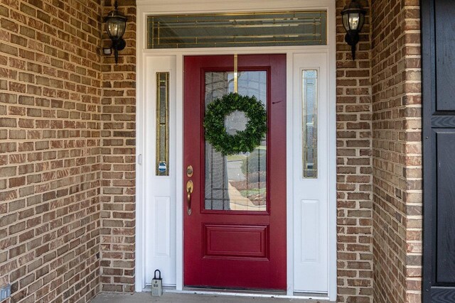 view of exterior entry with covered porch and brick siding